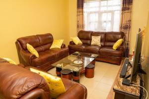 a living room with brown leather couches and a table at Bonaventure Apartment in Kisumu