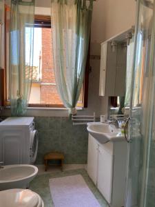 a bathroom with a sink and a toilet and a window at la scala di tutti in Asciano