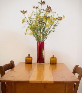 un jarrón de flores sentado sobre una mesa de madera en The River Bend Cottages, en Graaff-Reinet