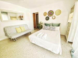 a white bedroom with a bed and a couch at ESTUDIO BLEGAMAR TERRAZA - Playa, WiFi y Aparcamiento in El Puerto de Santa María