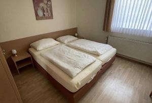 a bedroom with a bed with white sheets and a window at Haus Kiek Ut Apartment 22 in Timmendorfer Strand