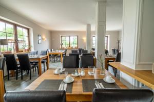 a dining room with tables and chairs and windows at Reetdachhotel - Residenz am Ostufer in Boek