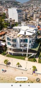 un gran edificio blanco con palmeras frente a una ciudad en Titania Hotel, en Sarandë