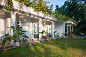 a white house with potted plants in a yard at Waters Spring in Kandy