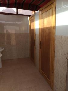 a bathroom with two wooden doors and a toilet at Bedouin Expedition in Wadi Rum