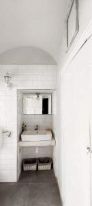 a white bathroom with a sink and a mirror at Godot Apartman in Miskolc
