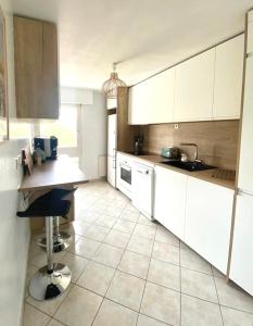 a kitchen with white cabinets and a tile floor at Chez Tata Emma in Annecy