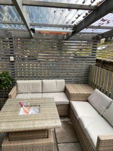 a patio with two couches and a table with a plate at Calderside Cottage (2 BDR Central Hebden Bridge) in Hebden Bridge