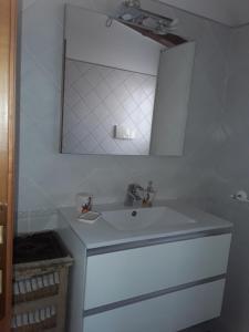 Baño blanco con lavabo y espejo en L'Onda en Oristano