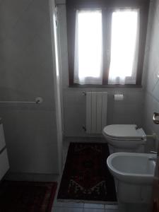 ein weißes Bad mit einem WC und einem Fenster in der Unterkunft L'Onda in Oristano