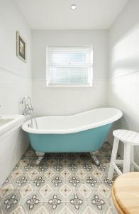 a bathroom with a blue bath tub and a table at Quiet Edwardian era House, Painswick in Painswick