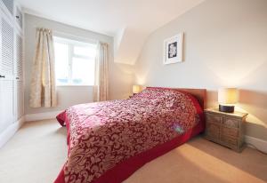 a bedroom with a red bed and a window at Quiet Edwardian era House, Painswick in Painswick
