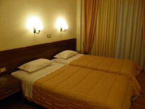 two beds in a hotel room with two lamps at Hotel Meletiou in Thiva