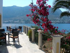 einen Balkon mit Tischen, Stühlen und rosa Blumen in der Unterkunft Hotel Porto Potha in Telendos