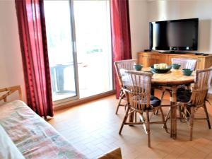 une salle à manger avec une table, des chaises et une télévision dans l'établissement Appartement Climatisé 2P avec Parking, Proche Plage et Commerces à Cavalaire - FR-1-226B-99, à Cavalaire-sur-Mer