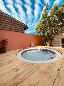 un bain à remous sur une terrasse en bois avec un arbre dans l'établissement Adorables studios - emplacement idéal, à Saint-Gilles-Croix-de-Vie