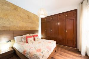 a bedroom with a large bed and wooden cabinets at Estupendo apartamento en segunda línea de playa in Torre de Benagalbón