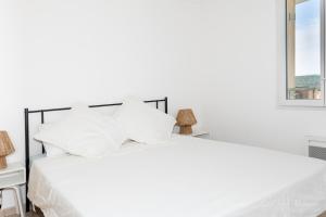 a white bed with white pillows and a window at Le Hameau in La Croix-Valmer