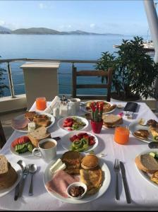 een tafel met borden met voedsel erop met uitzicht op de oceaan bij Titania Hotel in Sarandë