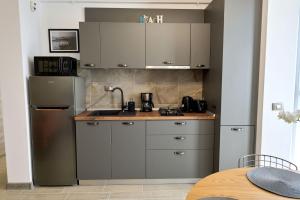 a kitchen with gray cabinets and a refrigerator at Vintage breeze Apartment - Spa Pools resort in Mamaia