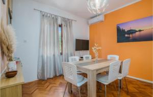 a dining room with a table and white chairs at Stunning Apartment In Bascanska Draga With Kitchen in Draga Bašćanska