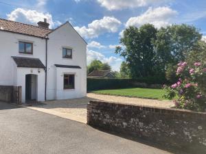 een wit huis met een tuin en een oprit bij Wensum Cottage in Norwich