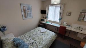 a small bedroom with a bed and a sink at Tennyson Lodge in Mablethorpe