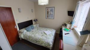 a small bedroom with a bed and a desk at Tennyson Lodge in Mablethorpe