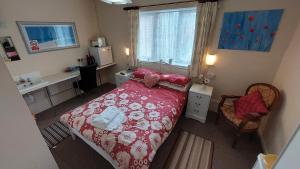 a bedroom with a bed and a desk and a window at Tennyson Lodge in Mablethorpe