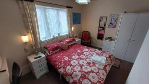 a bedroom with a red bed and a window at Tennyson Lodge in Mablethorpe