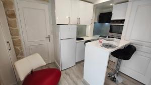 Elle comprend une petite cuisine avec des placards blancs et une chaise rouge. dans l'établissement Le Petit Paradis, à Brive-la-Gaillarde