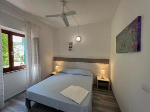 een slaapkamer met een bed, 2 tafels en een raam bij Azienda Agricola Sapereta in Porto Azzurro