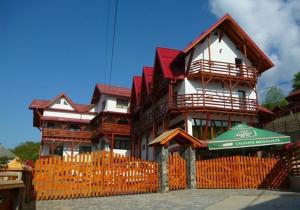a building with an orange fence and an umbrella at Pensiunea Valcinet in Borşa
