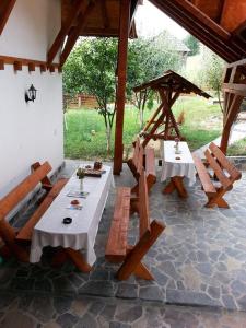 a patio with two tables and benches in a pavilion at Pensiunea Valcinet in Borşa