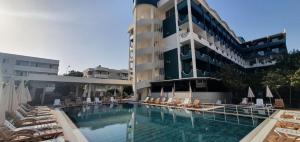 a hotel with a swimming pool and chairs and a building at Hedef Kleopatra Otel in Alanya