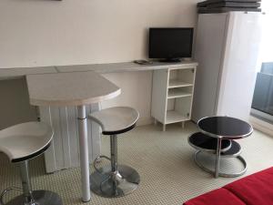 una camera con scrivania, due sgabelli e una televisione di Arcachon studio cabine avec accès direct à la plage ad Arcachon