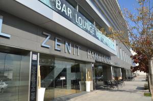 un magasin à l'avant d'un bâtiment muni d'un panneau. dans l'établissement Hotel Zenit Pamplona, à Cordovilla