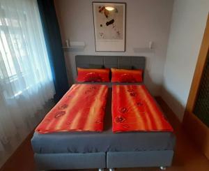 ein Bett mit roten Kissen in einem kleinen Zimmer in der Unterkunft Ferienwohnung "kleine galerie" in Königheim