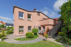 ein rosa Haus mit einer Treppe davor in der Unterkunft Ferienwohnungen Becker "Sonne & Meer" und "Strandliebe" in Kühlungsborn