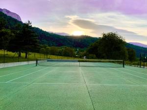 a tennis court with the sun setting in the background at LE NID DU BIRDIE, Giez, Proche du lac d’Annecy in Giez