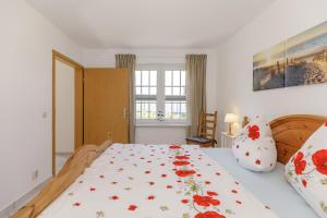 ein Schlafzimmer mit einem Bett mit geblümter Tagesdecke in der Unterkunft Ferienwohnungen Becker "Sonne & Meer" und "Strandliebe" in Kühlungsborn