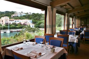a restaurant with tables and chairs and a large window at Hotel Palumbalza Porto Rotondo in Porto Rotondo