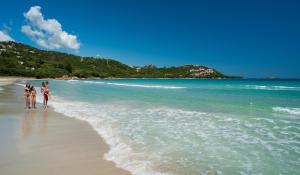 two people walking on a beach near the water at Hotel Palumbalza Porto Rotondo in Porto Rotondo