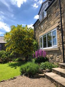 a stone house with purple flowers in the yard at Milburn House in Bellingham