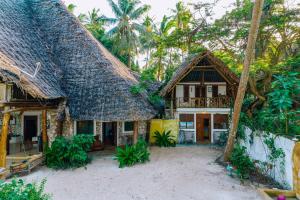 une maison avec un toit de chaume et des palmiers dans l'établissement Utupoa, à Matemwe