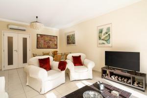 a living room with two chairs and a flat screen tv at Ria Olhao in Olhão