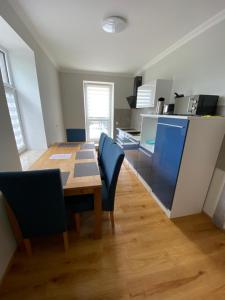 uma cozinha com uma mesa de madeira e cadeiras azuis em 2 Raum Apartment mit Terrasse, hell und stilvoll em Borna