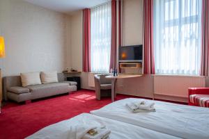 キューリッツにあるHotel & Restaurant Waldschlösschenのベッド、ソファ、テレビが備わるホテルルームです。