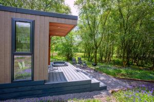 a house with a deck and two chairs in a yard at Ewe pod, luxury glamping pod with hot tub, Croft4glamping in Benderloch