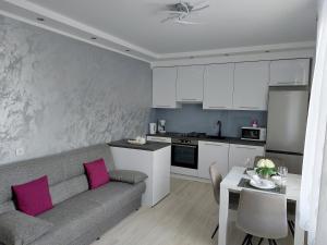 een woonkamer met een bank en een keuken met roze kussens bij Apartment Hrzic Malinska in Malinska